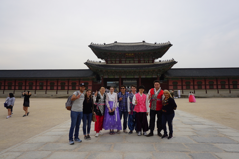 un grupo de personas caminando en una plaza con Gyeongbokgung de fondo