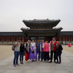 un grupo de personas caminando en una plaza con Gyeongbokgung de fondo